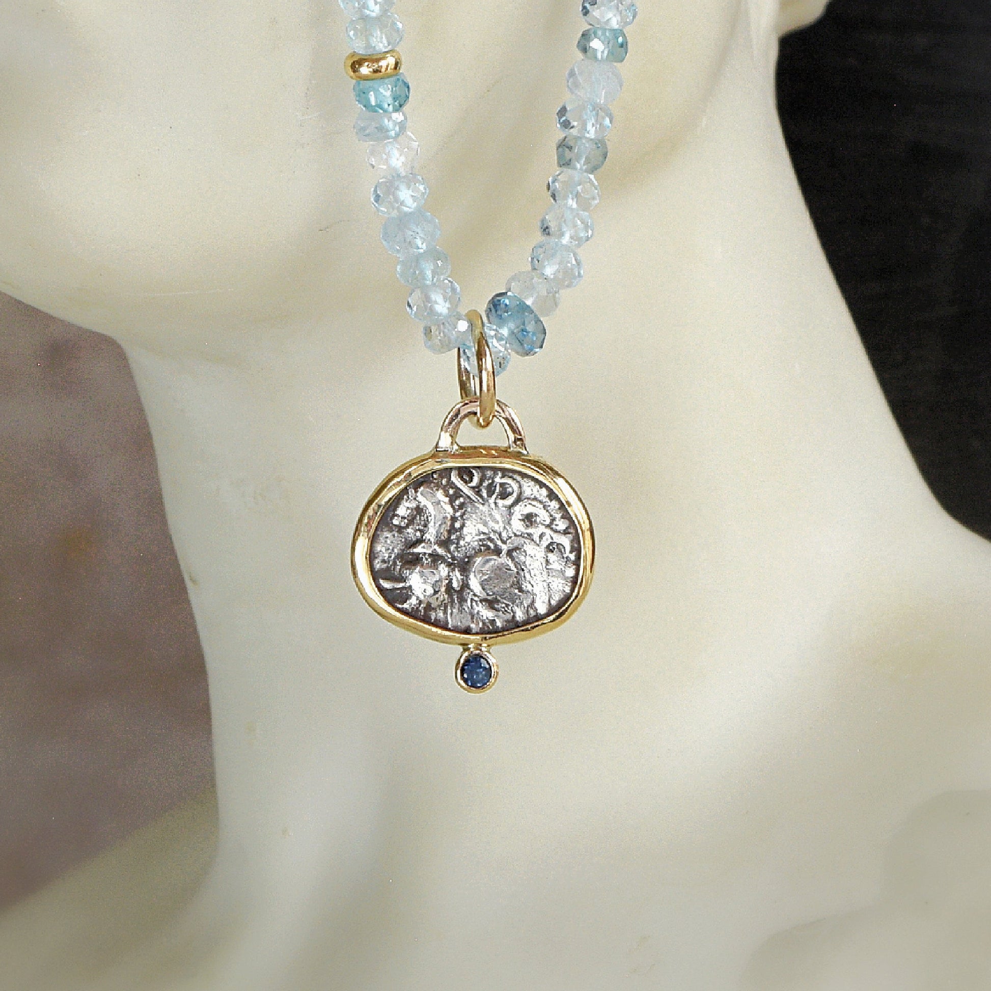 Ancient Celtic coin pendant with blue sapphire hanging on Aquamarine bead necklace with gold